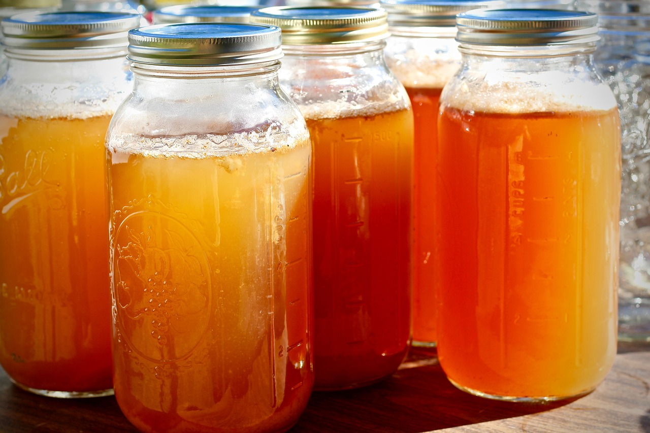 L'image représente une bouteille de vinaigre de cidre de pomme accompagnée de pommes fraîches, symbolisant les bienfaits du vinaigre de cidre de pomme dans le régime cétogène.