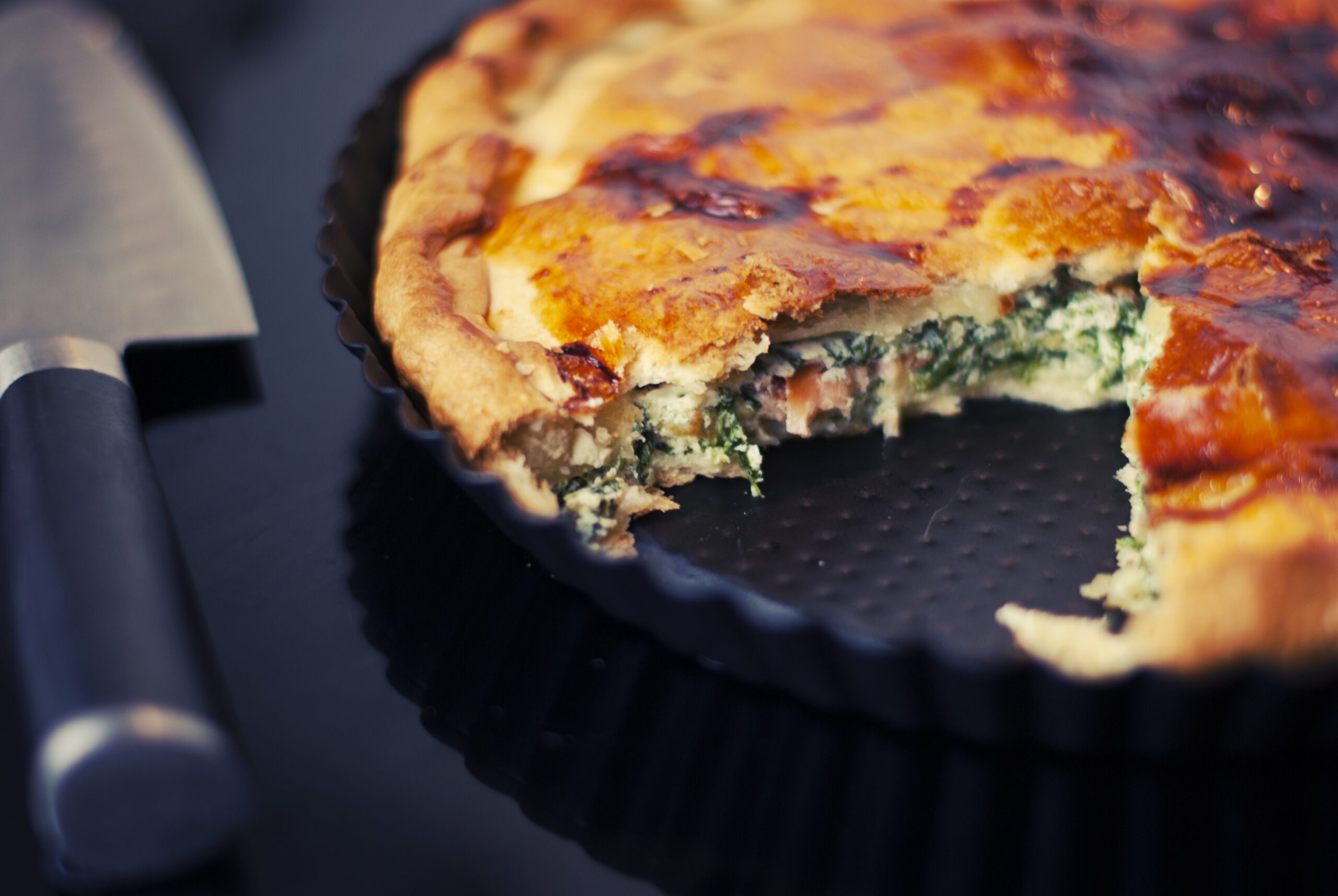 Image de deux quiches cétogènes : une garnie d'épinards frais, de fromage crémeux et d'œufs, l'autre avec des morceaux de jambon fumé, d'oignons doux et de fromage fondant, des options appétissantes pour un repas cétogène équilibré.